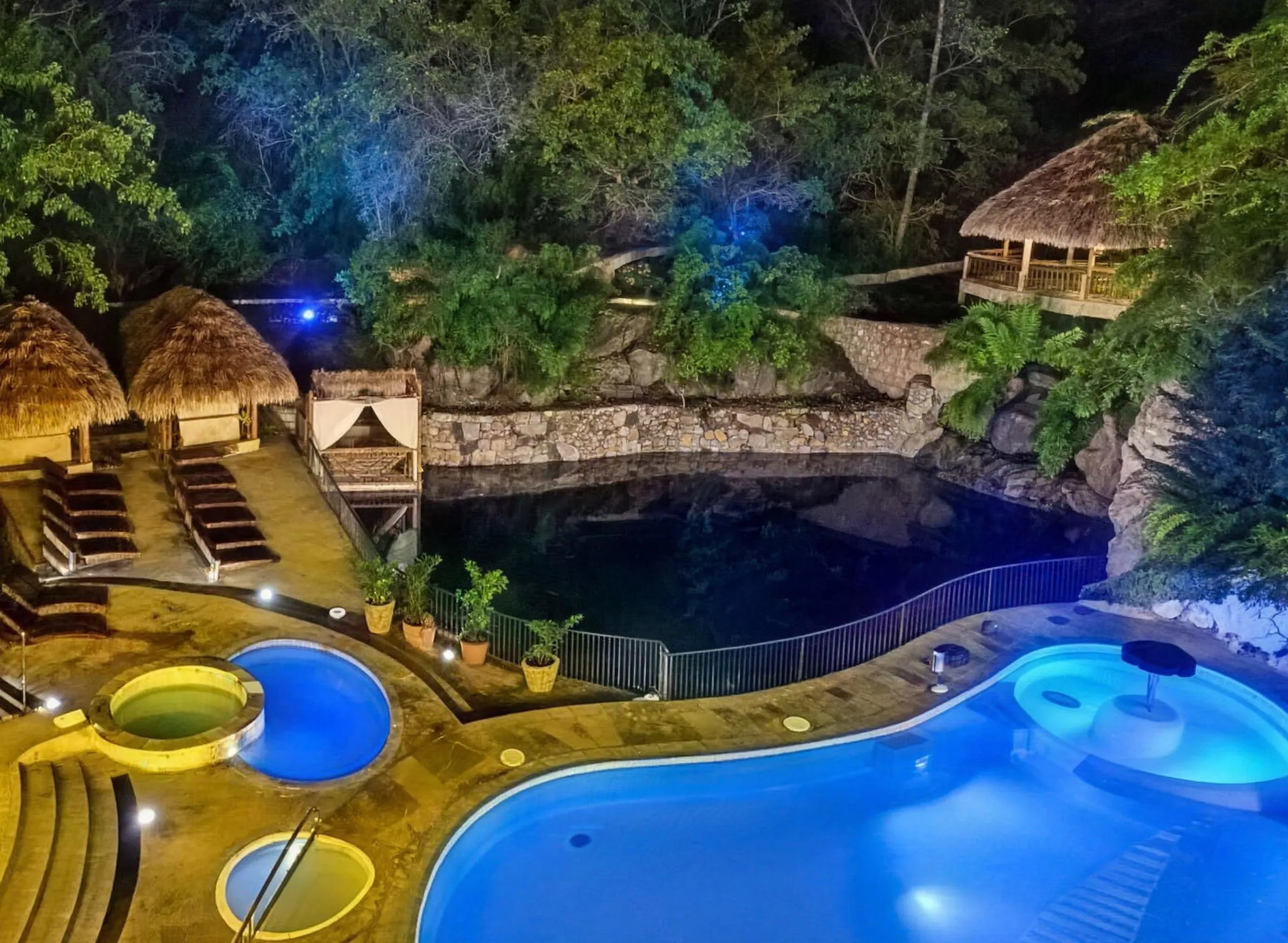Piscinas iluminadas del resort entre vegetación tropical de noche